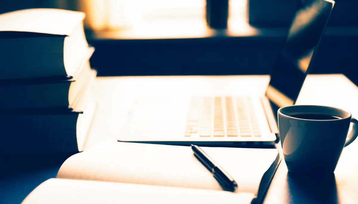 Schreibtisch mit Büchern, Notizen und Laptop – Versicherung für Beamtenanwärter
